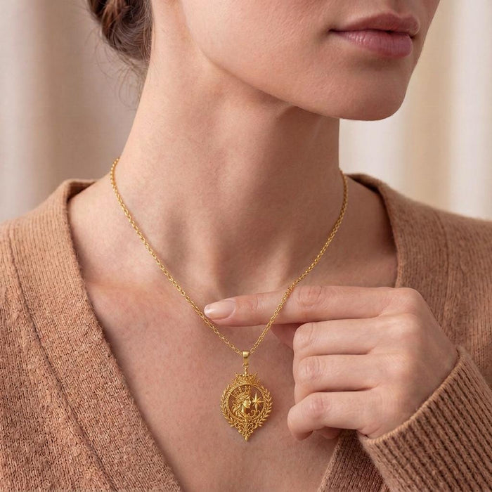 Model wearing the gold-finish Celestial Queen Emblem Pendant necklace at the collarbone with a neutral knit top