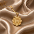 Gold Plated Silver Crown Seal Pendant Necklace with crowned emblem and laurel branches on champagne satin