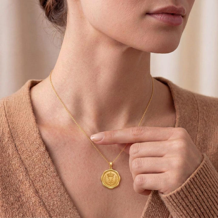 Close-up of a model wearing and holding a Gold Plated Silver Crown Seal Pendant Necklace