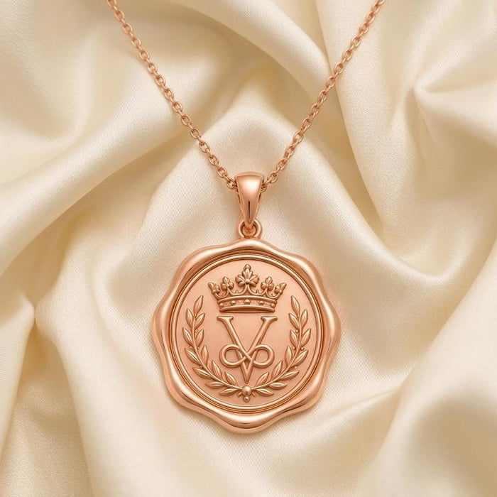 Rose-toned Crown Seal Pendant Necklace displayed on ivory satin