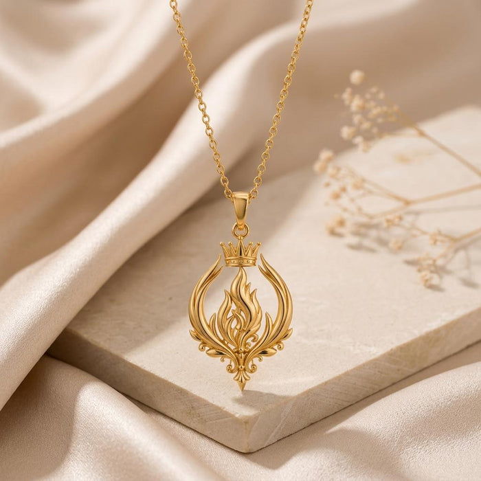 Gold Plated Silver Empress Flame Crest Necklace displayed on a pale stone block with champagne satin