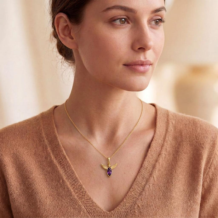 Woman wearing a Gold Plated Silver Angel Wing Necklace with a purple marquise-shaped center stone and tan V-neck knit