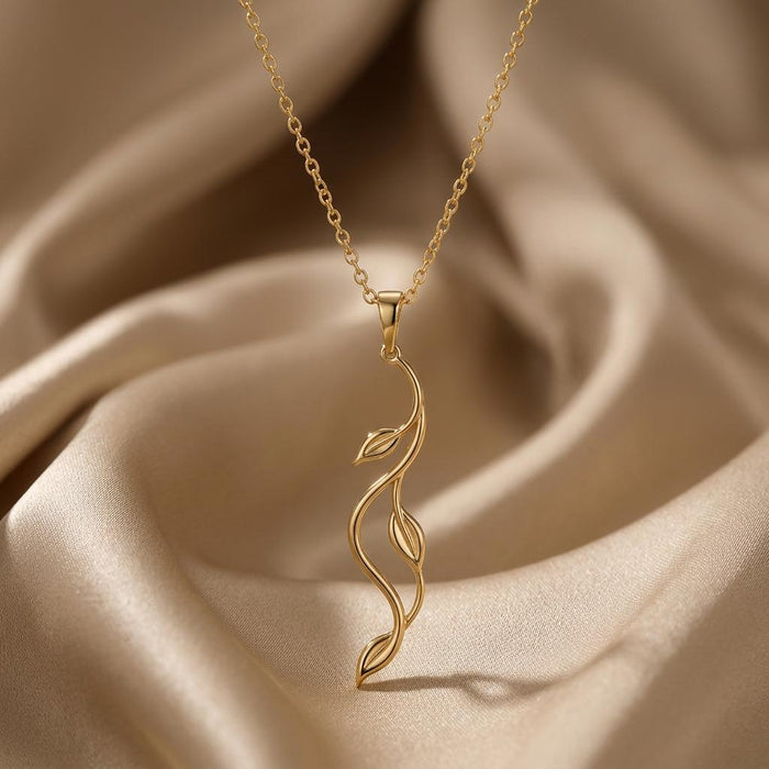 Gold Plated Silver Aurora Vine Necklace with a vertical openwork vine pendant displayed on champagne satin