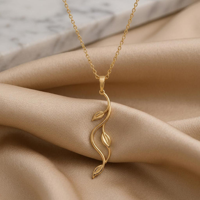 Gold Plated Silver Aurora Vine Necklace close-up on champagne satin beside a marble background