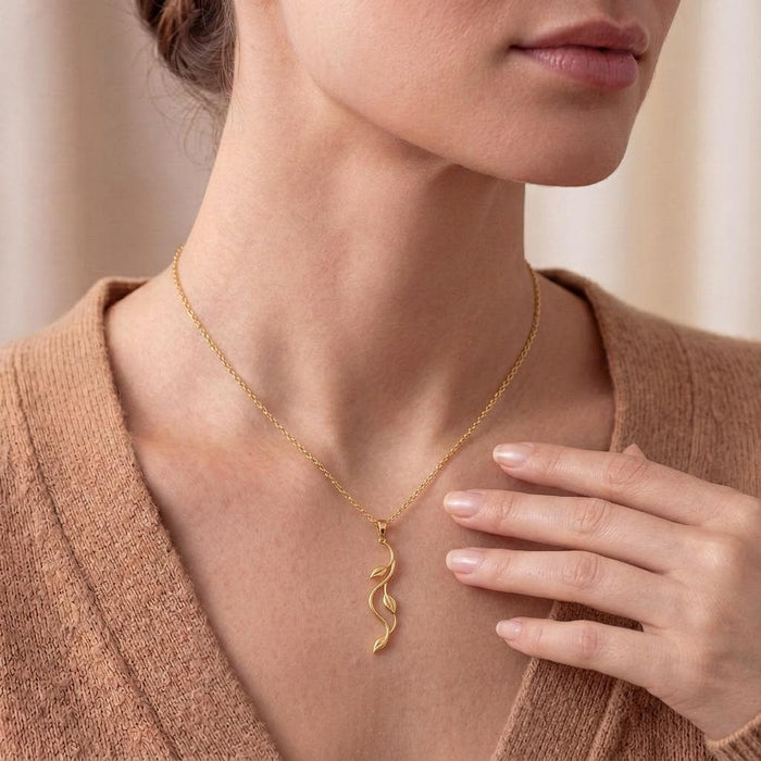 Gold Plated Silver Aurora Vine Necklace worn with a knit top and a hand near the pendant