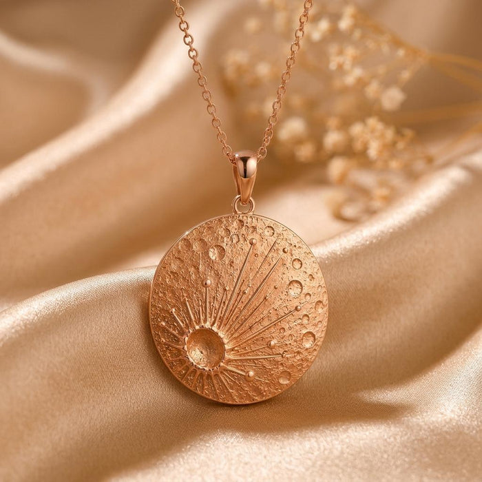 Rose Gold Plated Lunar Impact Pendant close-up with a crater-textured disc on champagne satin beside dried flowers
