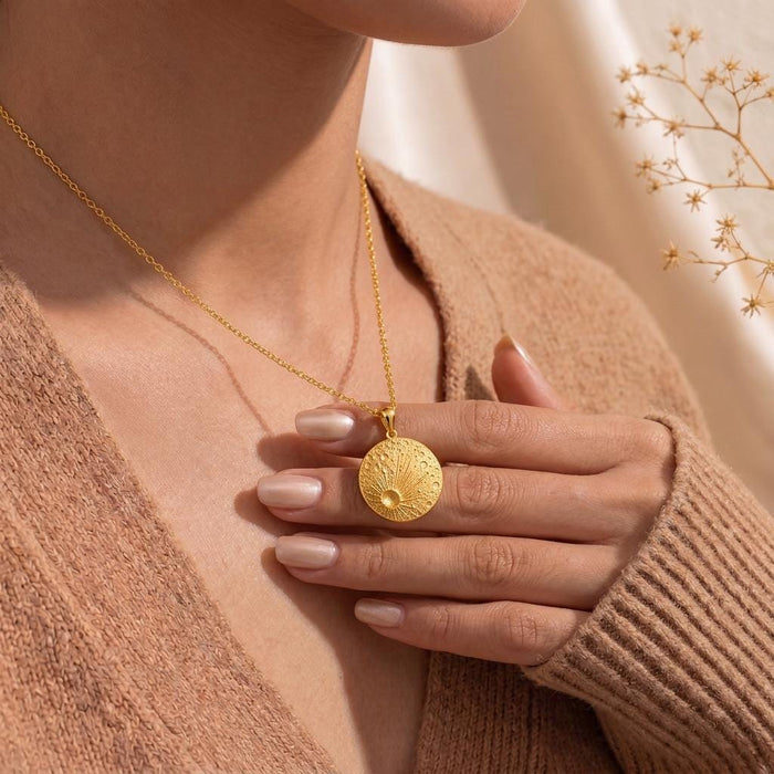 Gold Plated Silver Lunar Impact Pendant worn against a knit top with a hand holding the pendant