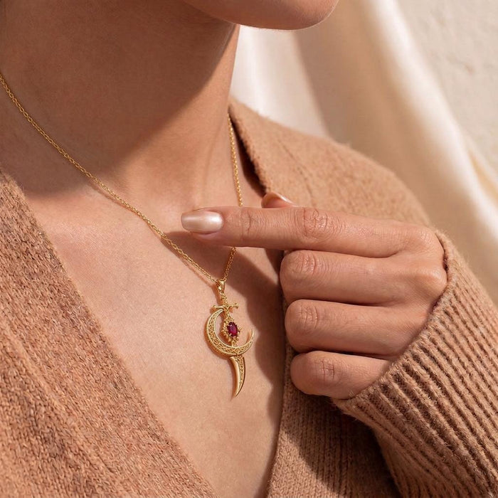 Close worn view of a Moonblade pendant necklace with a hand touching the chain