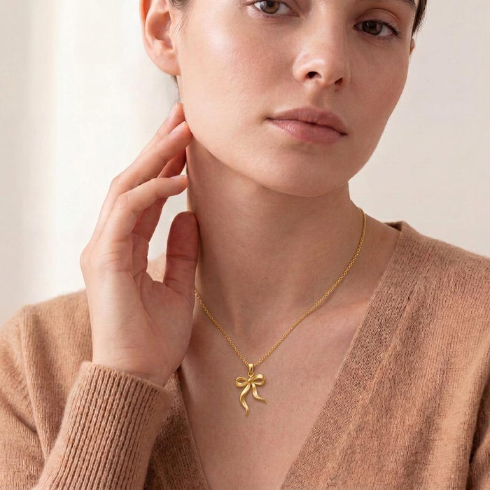 Gold Plated Silver Ribbon Flow Necklace worn at the neckline with an open ribbon-bow pendant