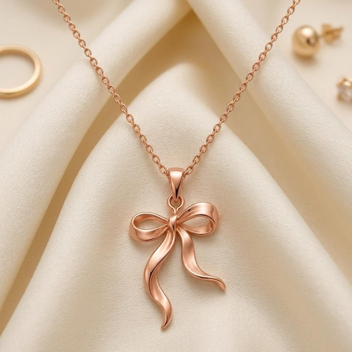 Rose Gold Plated Ribbon Flow Necklace with an open ribbon bow on ivory fabric