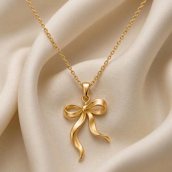 Gold Plated Silver Ribbon Flow Necklace close-up with a long wavy tail and outward-curving tail on ivory satin