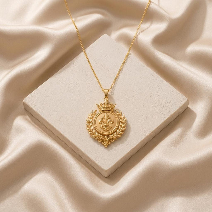 Gold Plated Silver Royal Laurel Sigil Pendant displayed on a square stone block surrounded by champagne-colored satin