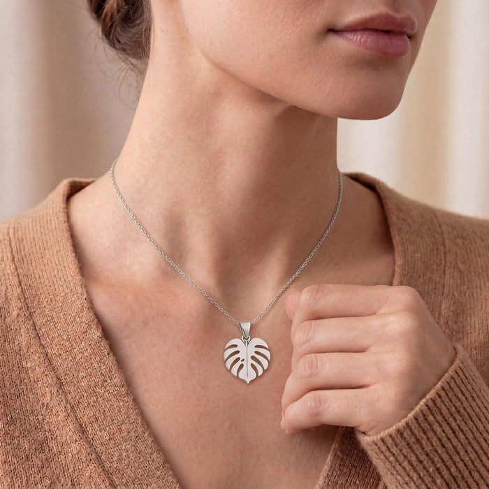 Three-quarter lifestyle view of the Monstera necklace worn over warm brown knitwear