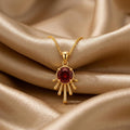 Gold Plated Silver Sun Drop Pendant Necklace with a deep red round center on champagne satin